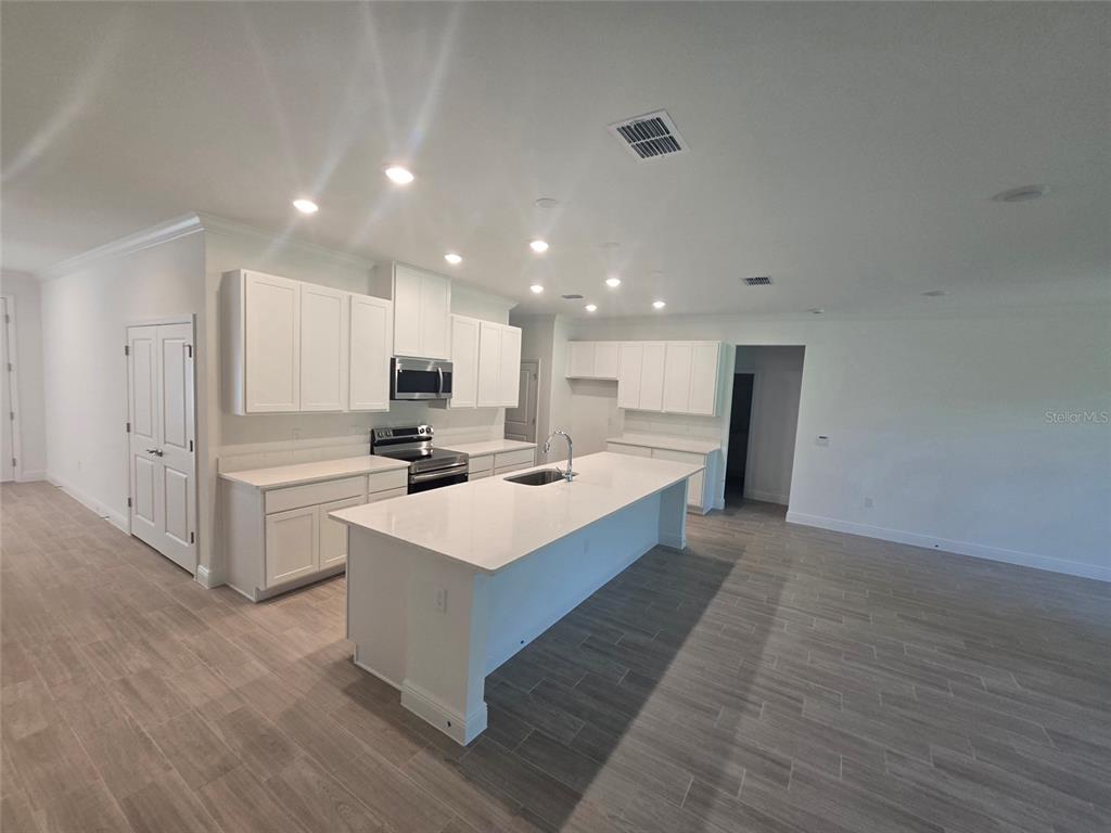 A side view of a single-story house with tan stucco walls, stone accents, and a sidewalk — 2631 FAIRFAX AVENUE, NEW SMYRNA BEACH, FL