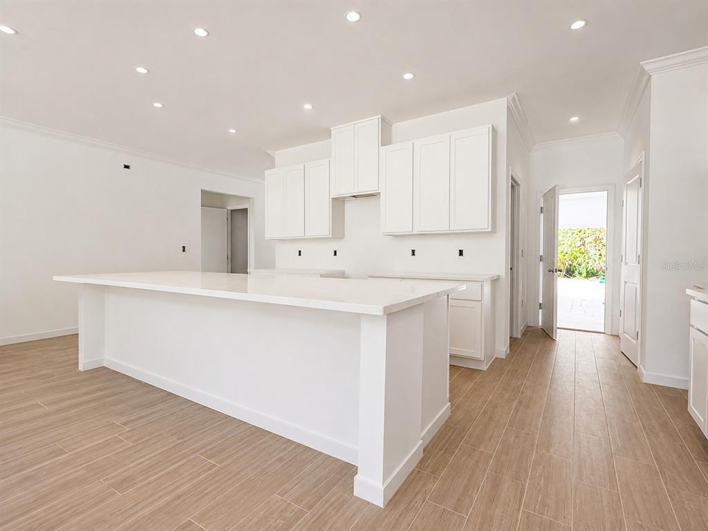 A modern kitchen features white cabinetry, a large quartz island with bar seating, and stainless appliances — 2631 FAIRFAX AVENUE, NEW SMYRNA BEACH, FL