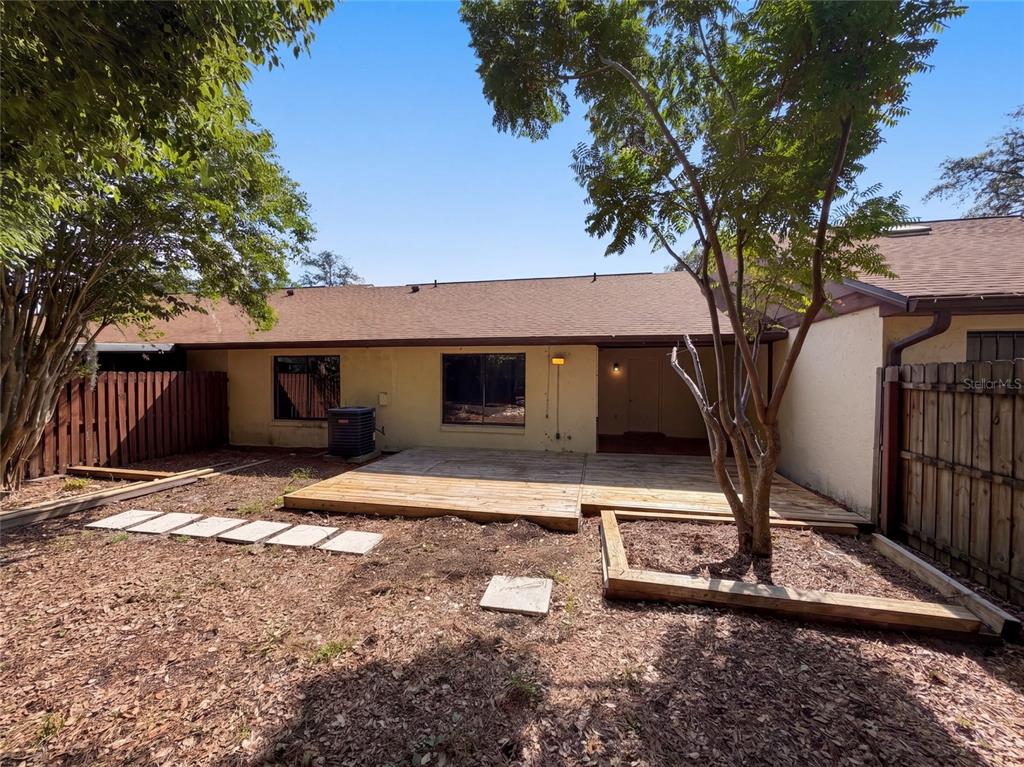 A backyard features a wooden deck, a tree, a fence, and a house exterior — 190 PINE KNOLL COURT, CASSELBERRY, FL