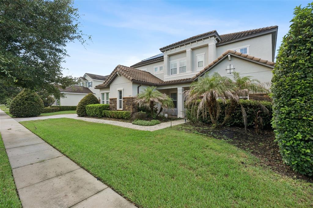 A two-story suburban house with a tiled roof, stone accents, and a landscaped front yard — 7693 GREEN MOUNTAIN WAY, WINTER GARDEN, FL
