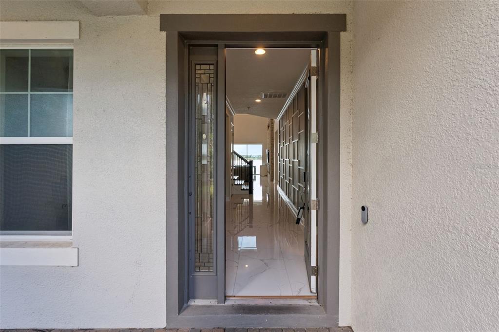 An open front door reveals a tiled entryway with a decorative wall and a staircase — 7693 GREEN MOUNTAIN WAY, WINTER GARDEN, FL