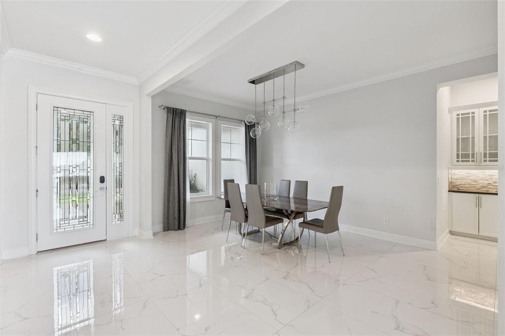 A dining room with a marble-tiled floor, a modern glass table, and a contemporary chandelier — 7693 GREEN MOUNTAIN WAY, WINTER GARDEN, FL
