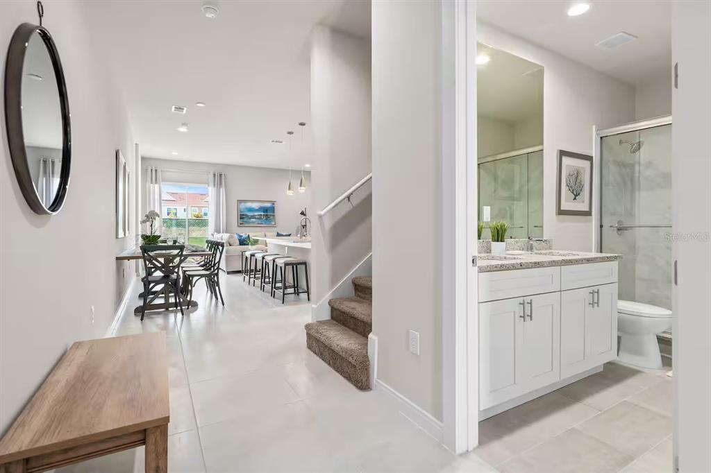 A hallway leads to an open-concept kitchen and dining area next to a full bathroom — 7568 SUNFLOWER CIRCLE, KISSIMMEE, FL