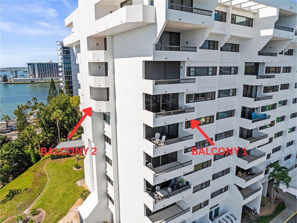 An aerial view of a white multi-story apartment building with two balconies highlighted by arrows — 30 TURNER STREET UNIT 704, CLEARWATER, FL