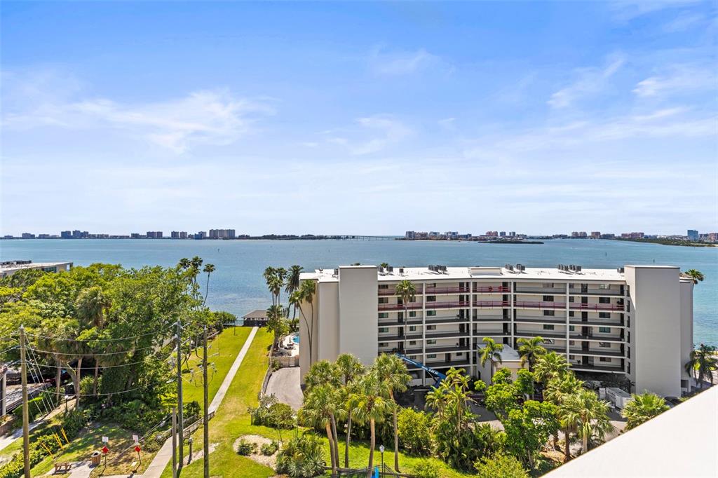 An elevated exterior view shows a multi-story apartment building overlooking a large body of water — 30 TURNER STREET UNIT 704, CLEARWATER, FL