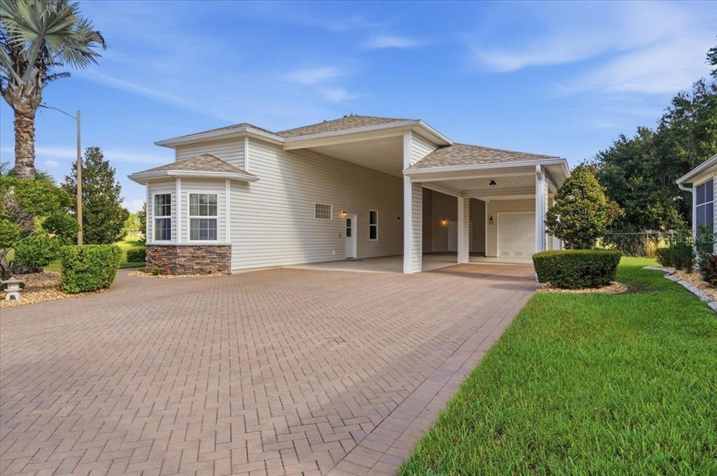 A beige house with a stone-accented bay window and a large covered carport area — 194 LAYNEWADE ROAD, POLK CITY, FL