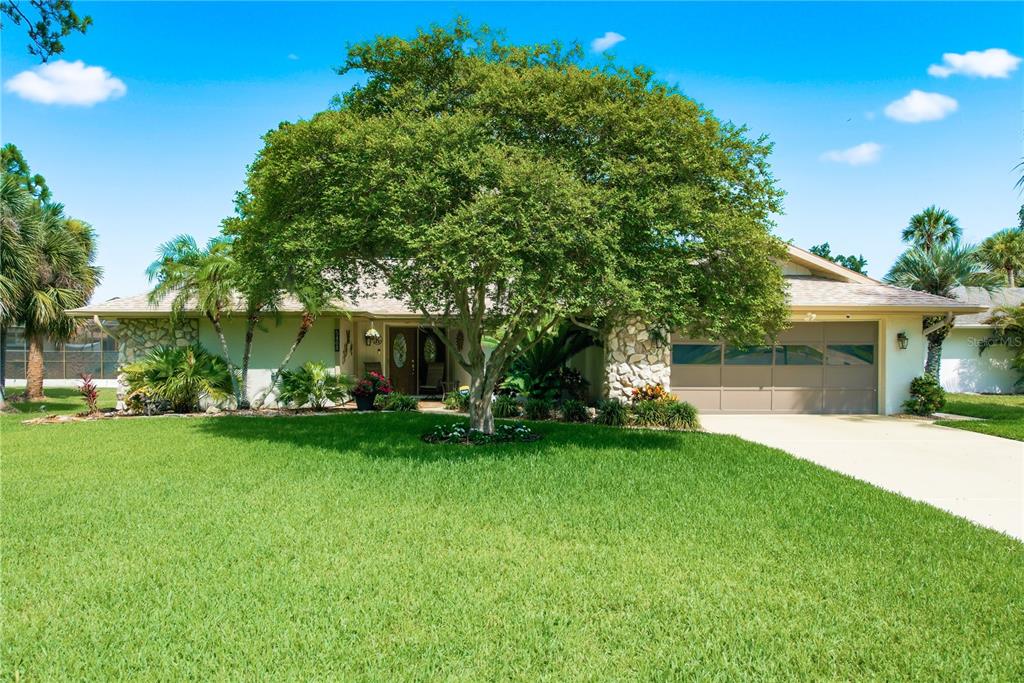 A single-story house with a large tree, stone accents, and a two-car garage — 5468 NIMITZ ROAD, NEW PORT RICHEY, FL