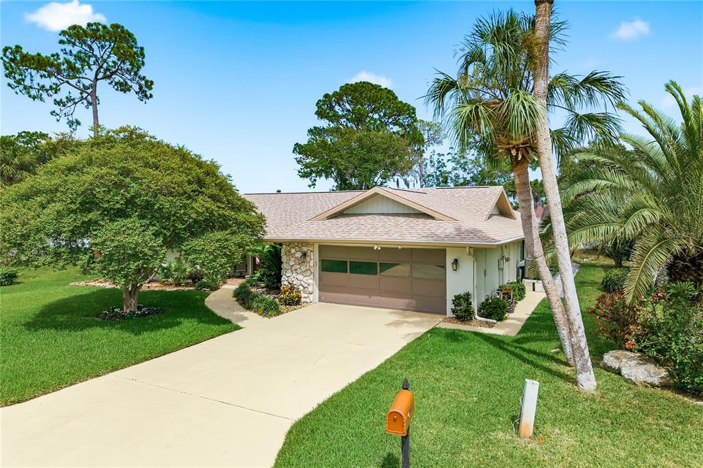 A single-story house with a beige garage, stone accents, and a palm tree in front — 5468 NIMITZ ROAD, NEW PORT RICHEY, FL