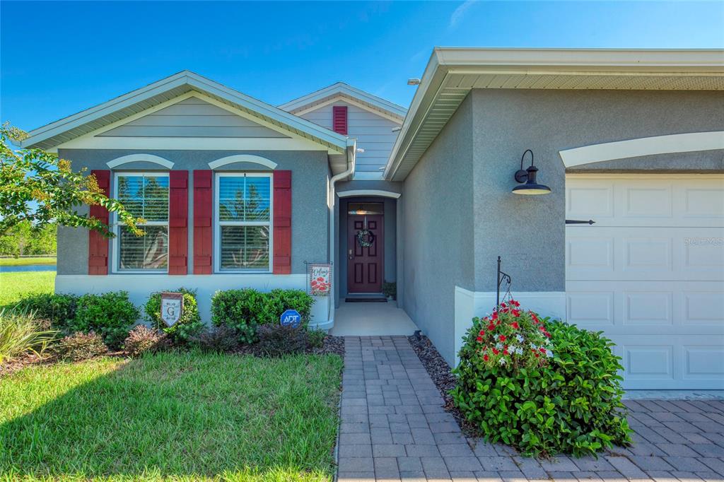 The exterior of a single-story house features a paved walkway, garage, and red shutters — 6 FOX LAIR COURT, ORMOND BEACH, FL
