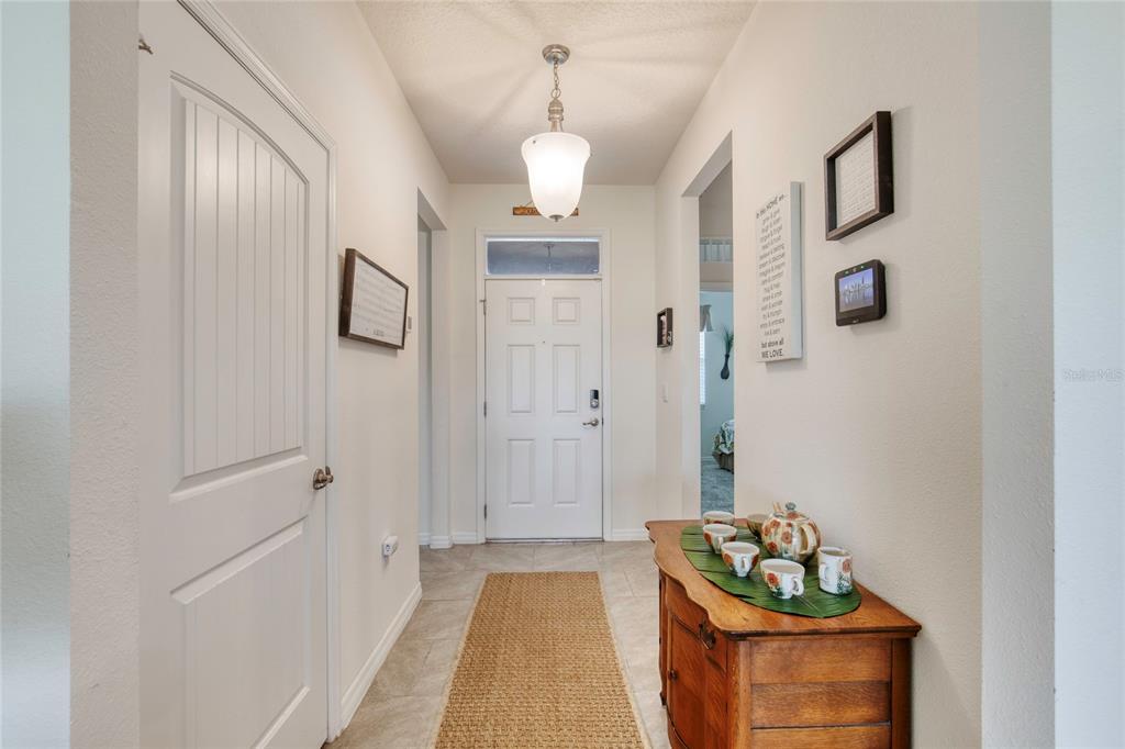 A foyer features a white front door, tile flooring, a runner rug, and a wooden console — 6 FOX LAIR COURT, ORMOND BEACH, FL
