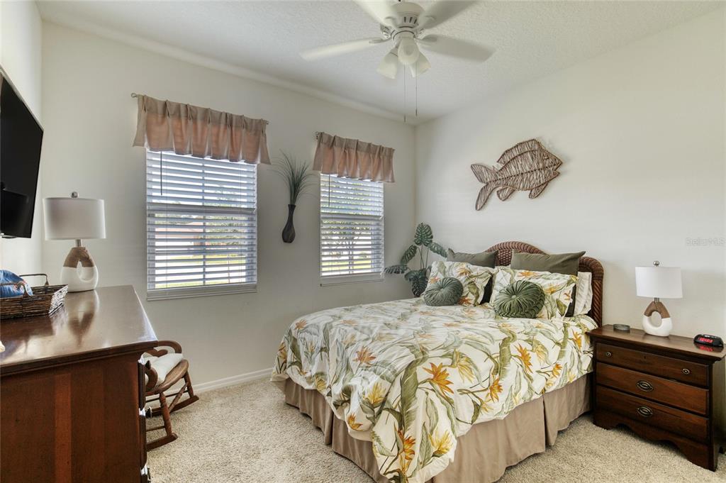 A bedroom features a queen bed with floral bedding, a wooden dresser, and two windows — 6 FOX LAIR COURT, ORMOND BEACH, FL