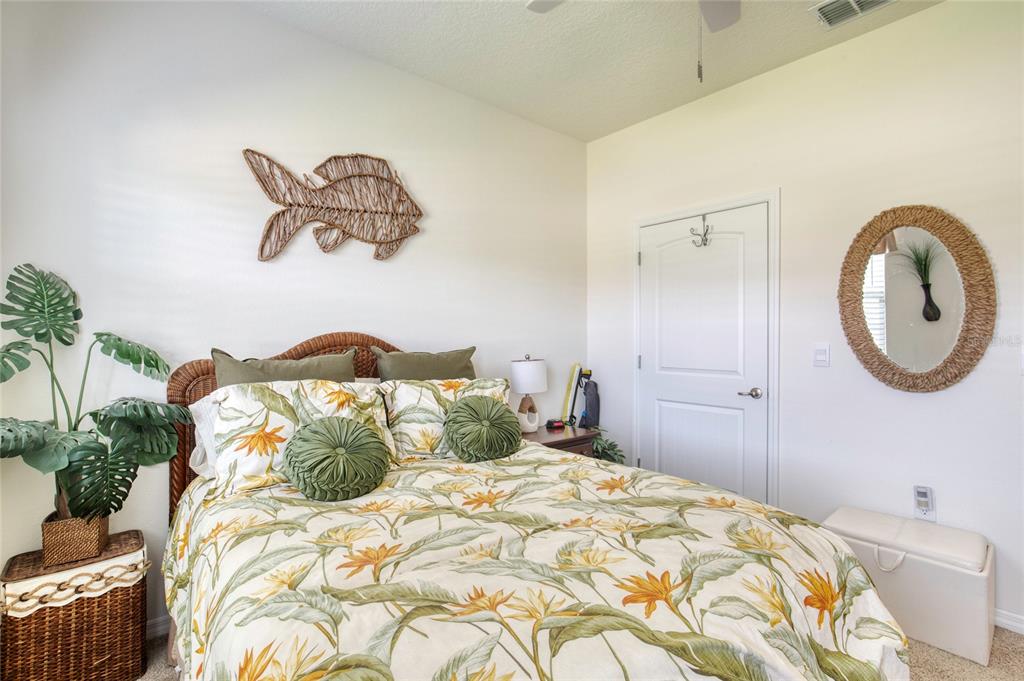 A bedroom features a floral-patterned bed, a wicker headboard, a fish wall decoration, and a mirror — 6 FOX LAIR COURT, ORMOND BEACH, FL