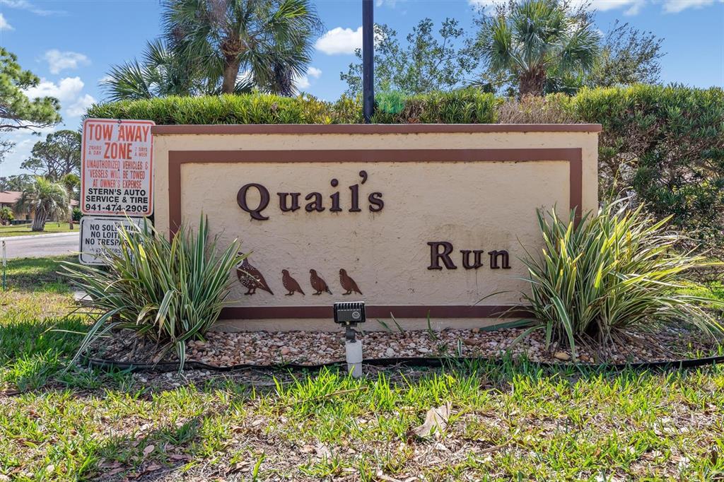 A beige monument sign for Quail's Run stands in a landscaped area with palm trees — 2 QUAILS RUN BOULEVARD UNIT 8, ENGLEWOOD, FL