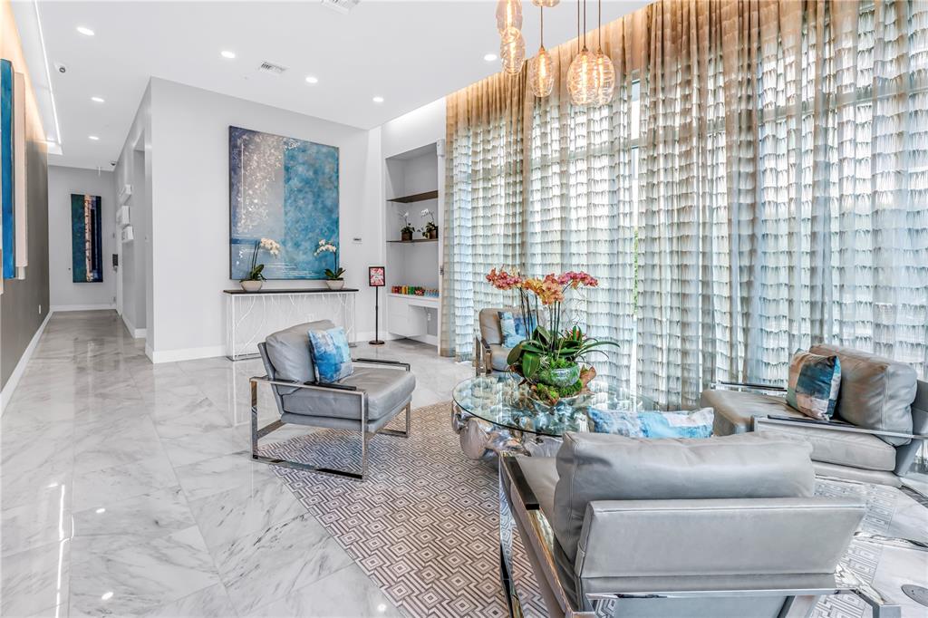 A modern living room features gray leather chairs, a glass coffee table, and floor-to-ceiling curtains — 176 4TH AVENUE NE UNIT 1101, ST PETERSBURG, FL