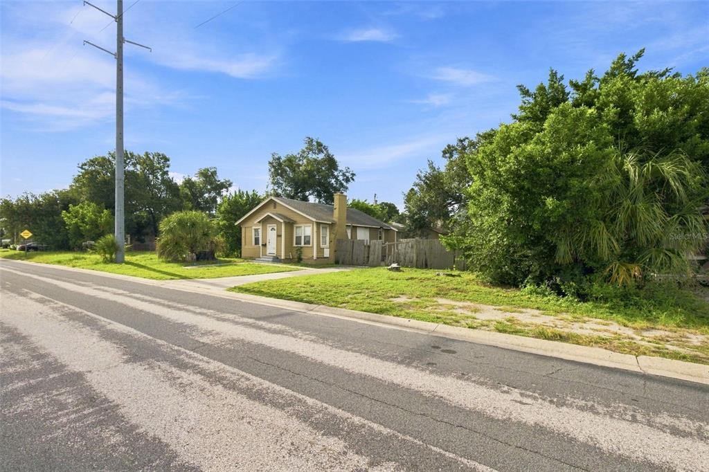 A small, tan, single-story house sits on a grassy lot next to a paved road — 2848 EMERSON AVENUE S, ST PETERSBURG, FL
