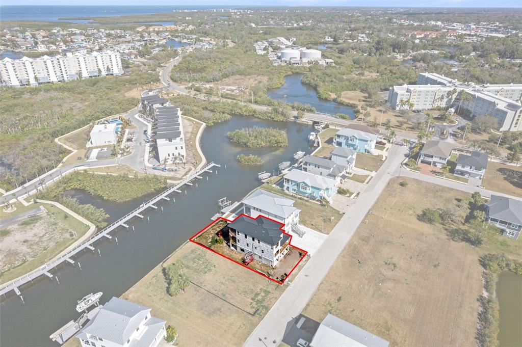 An aerial view shows two modern houses under construction near a canal and coastal landscape — 5815 ELISABETHAN LANE, NEW PORT RICHEY, FL