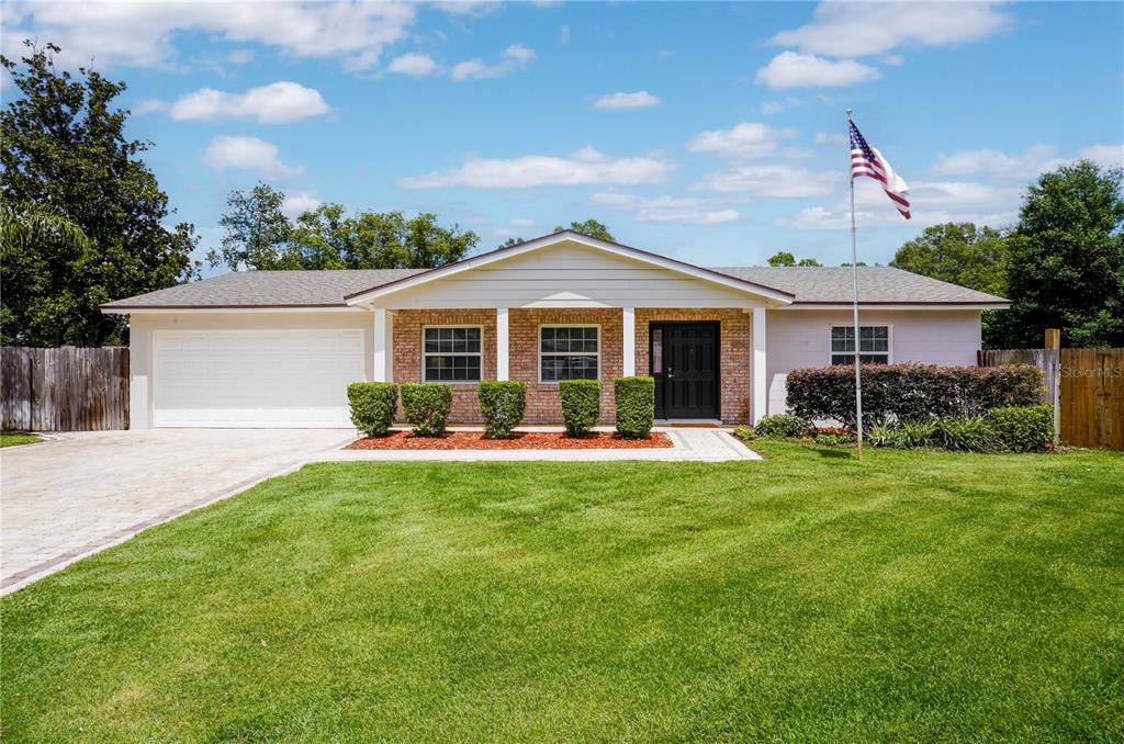 A single-story house with a brick facade, white siding, a two-car garage, and a lawn — 110 DEVON COURT, LONGWOOD, FL