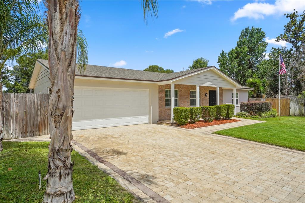 A single-story house with a brick facade, a paved driveway, and a white garage door — 110 DEVON COURT, LONGWOOD, FL