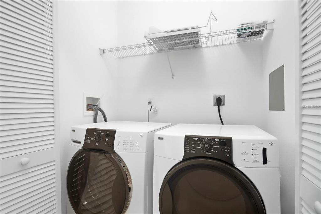 A laundry room featuring a white washer and dryer set beneath a wire storage shelf — 8168 BOAT HOOK LOOP UNIT 302, WINDERMERE, FL