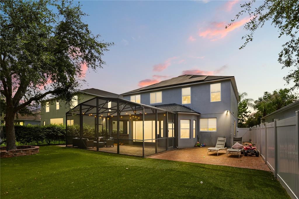 A two-story house with a screened-in patio, brick terrace, and artificial turf backyard at dusk — 932 LOST GROVE CIRCLE, WINTER GARDEN, FL