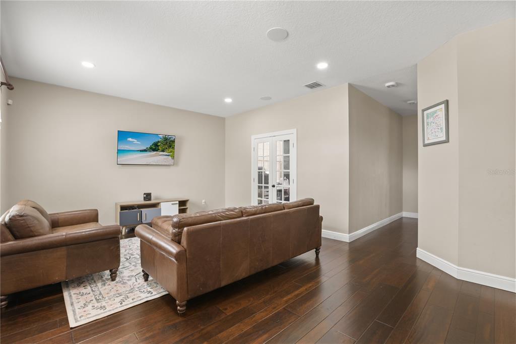 A living room features dark wood floors, a leather sofa, and a wall-mounted television — 932 LOST GROVE CIRCLE, WINTER GARDEN, FL