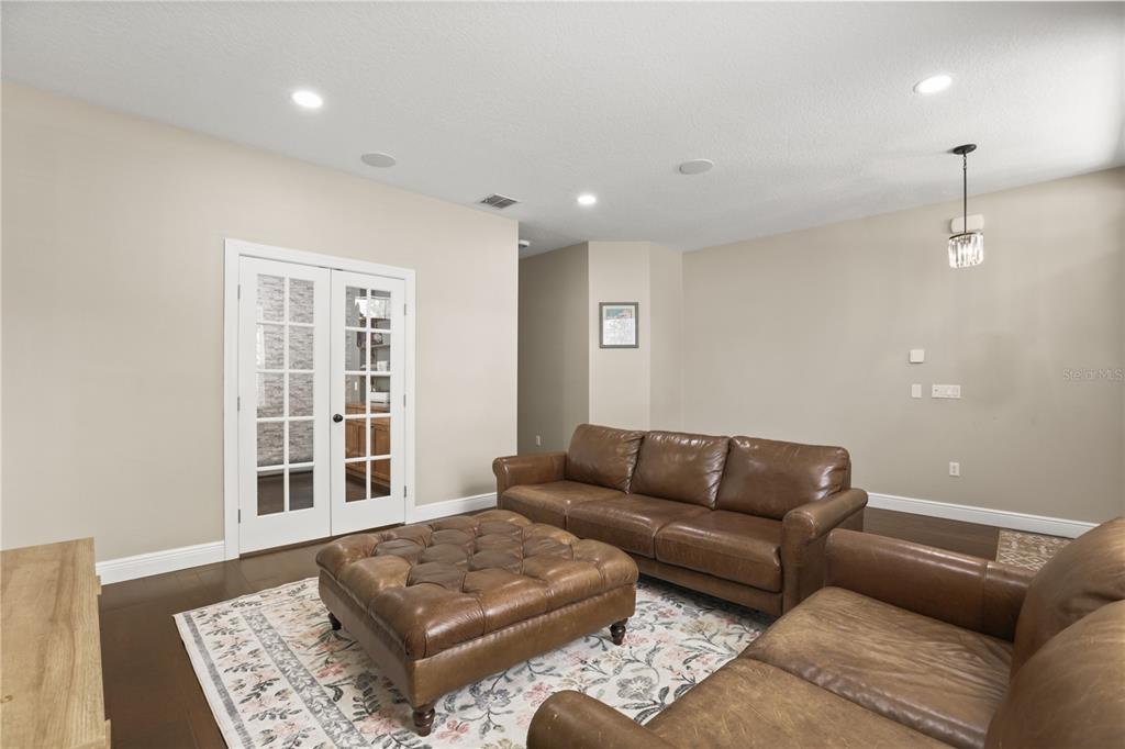 A living room features brown leather sofas, a tufted ottoman, and French doors — 932 LOST GROVE CIRCLE, WINTER GARDEN, FL