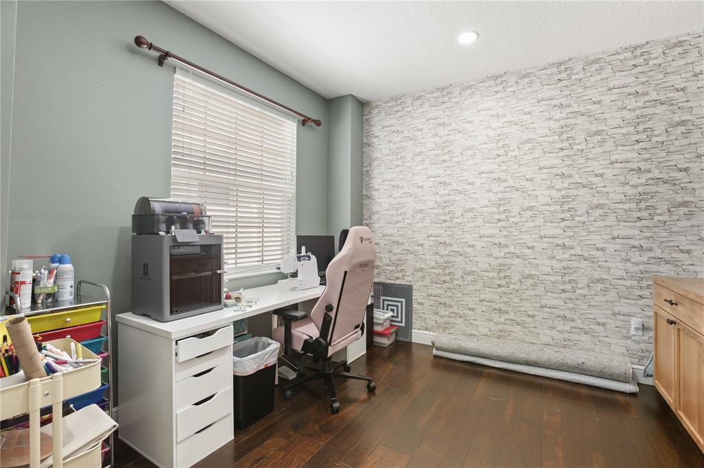 A home office features a desk, a pink gaming chair, and a stone-patterned accent wall — 932 LOST GROVE CIRCLE, WINTER GARDEN, FL