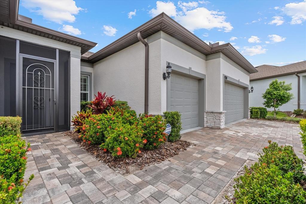 The exterior of a house features a paved driveway, two garage doors, and landscaped bushes — 8510 COASTAL PALMS GLEN, PARRISH, FL