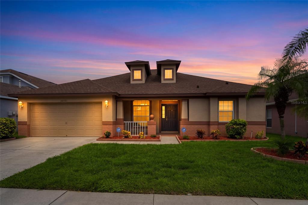 A tan house with a screened-in patio and a white vinyl fence in the backyard — 30501 IVERSON DRIVE, WESLEY CHAPEL, FL