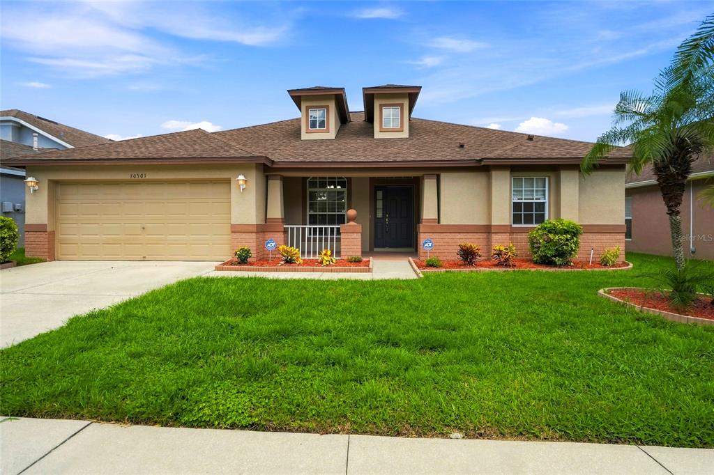 A single-story house with a tan exterior, a palm tree, and a green lawn — 30501 IVERSON DRIVE, WESLEY CHAPEL, FL