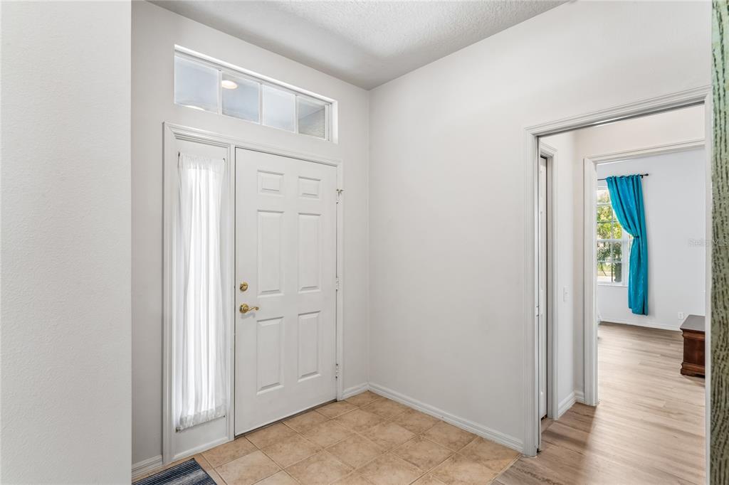 A bright entryway features a white front door with a sidelight and tile flooring — 14466 TAMARIND LOOP, SPRING HILL, FL