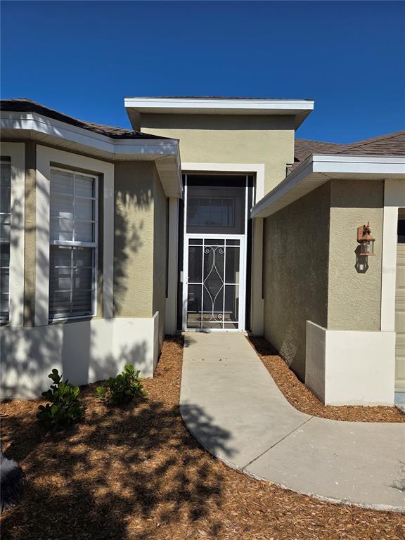 A concrete walkway leads to the front entrance of a house with a screen door — 5202 72ND STREET E, PALMETTO, FL