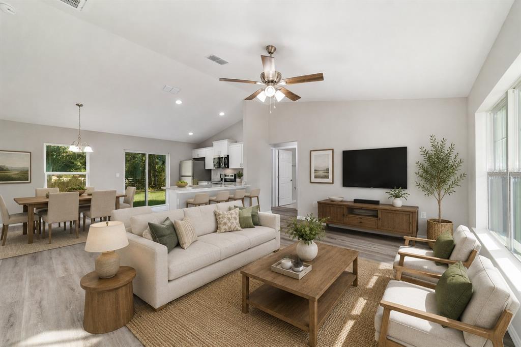 An open-concept living area with light wood-look flooring, vaulted ceilings, and a kitchen island — 44 ALMOND ROAD, OCALA, FL