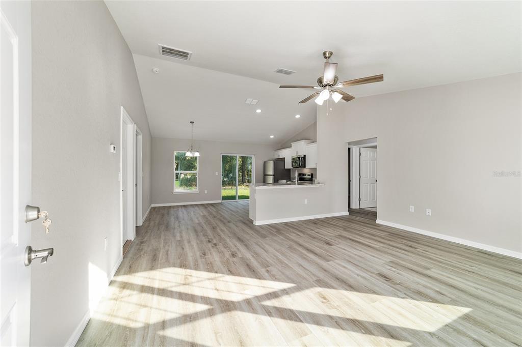 A modern kitchen features white cabinets, stainless steel appliances, marble-look countertops, and wood-look flooring — 44 ALMOND ROAD, OCALA, FL