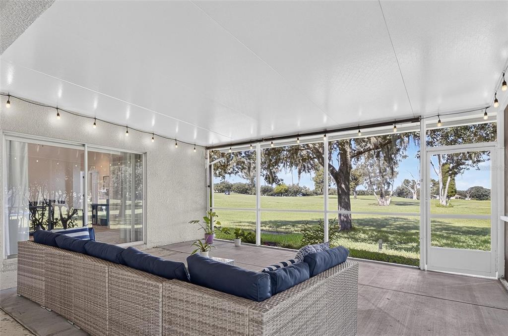 A covered patio with a wicker sectional sofa overlooks a grassy golf course — 1438 EMERALD HILL WAY, VALRICO, FL
