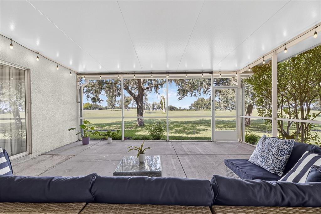 A screened-in patio with a concrete floor, wicker furniture, and a view of a golf course — 1438 EMERALD HILL WAY, VALRICO, FL