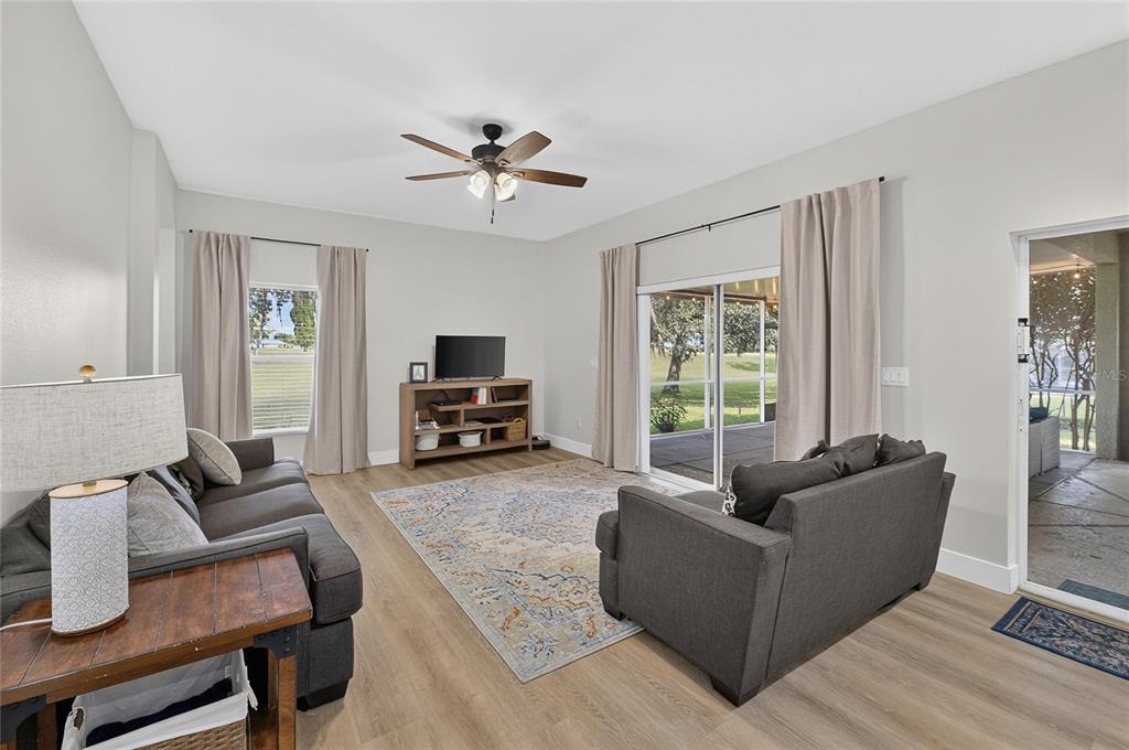 A living room features gray sofas, a wood media console, and sliding glass doors to a patio — 1438 EMERALD HILL WAY, VALRICO, FL