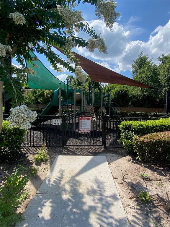 A fenced playground with a green slide and shade sails sits at the end of a path — 2130 PINE OAK TRAIL, SANFORD, FL