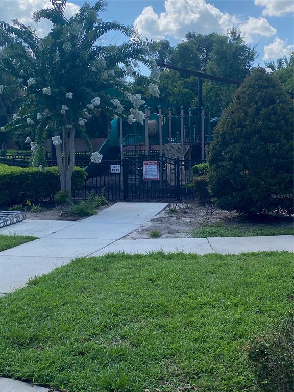 A fenced playground with a slide and climbing structure sits behind a paved walkway — 2130 PINE OAK TRAIL, SANFORD, FL