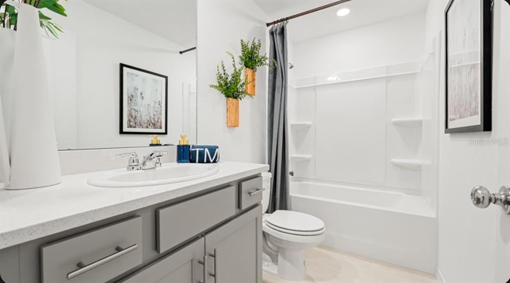 A modern open-concept kitchen and living area featuring gray cabinetry, a large island, and tile flooring — 7203 GRAND FOREST WAY, NOKOMIS, FL