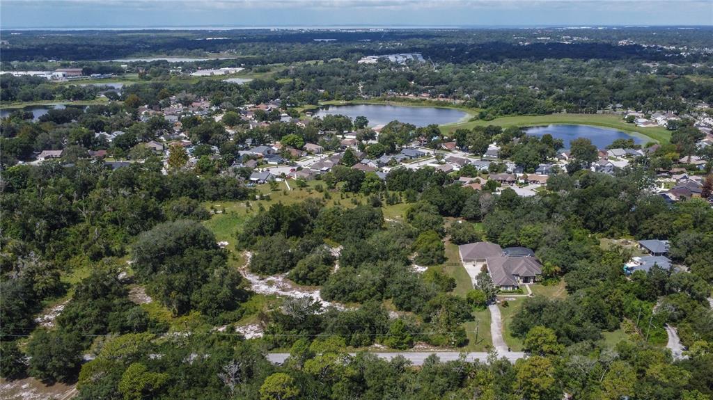 An aerial view shows a residential property with a house, driveway, and surrounding wooded landscape — 1156 HIGHLAND ACRES DRIVE, APOPKA, FL