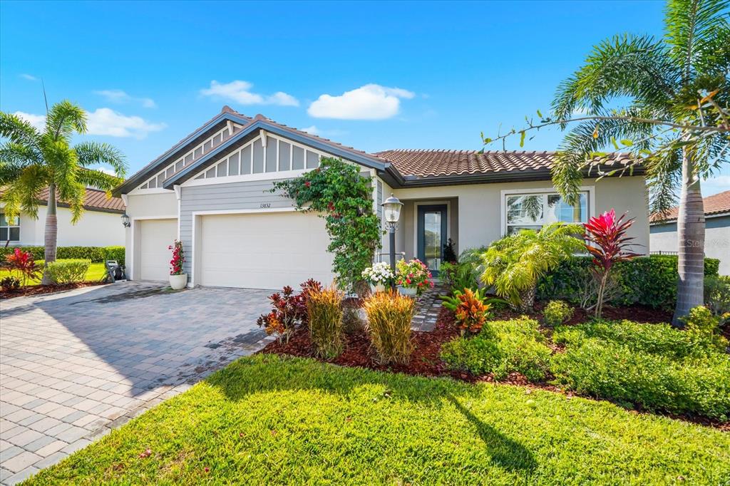 A single-story house with a paved driveway, two garage doors, and palm trees — 13832 GREEN HAMMOCK PLACE, BRADENTON, FL