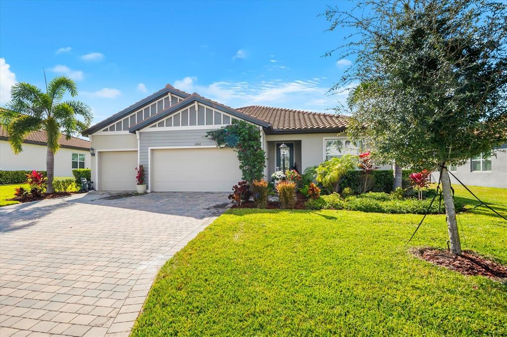 A single-story house with a paved driveway, a three-car garage, and palm trees — 13832 GREEN HAMMOCK PLACE, BRADENTON, FL