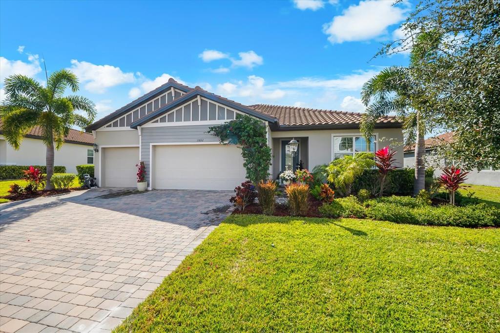 A single-story house with a paved driveway, a two-car garage, and landscaped front yard — 13832 GREEN HAMMOCK PLACE, BRADENTON, FL
