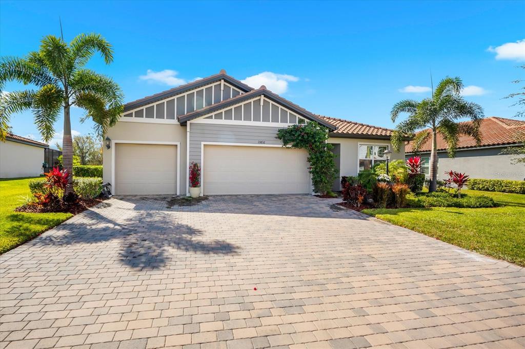 A single-story house with a two-car garage, a paved driveway, and a landscaped front yard — 13832 GREEN HAMMOCK PLACE, BRADENTON, FL