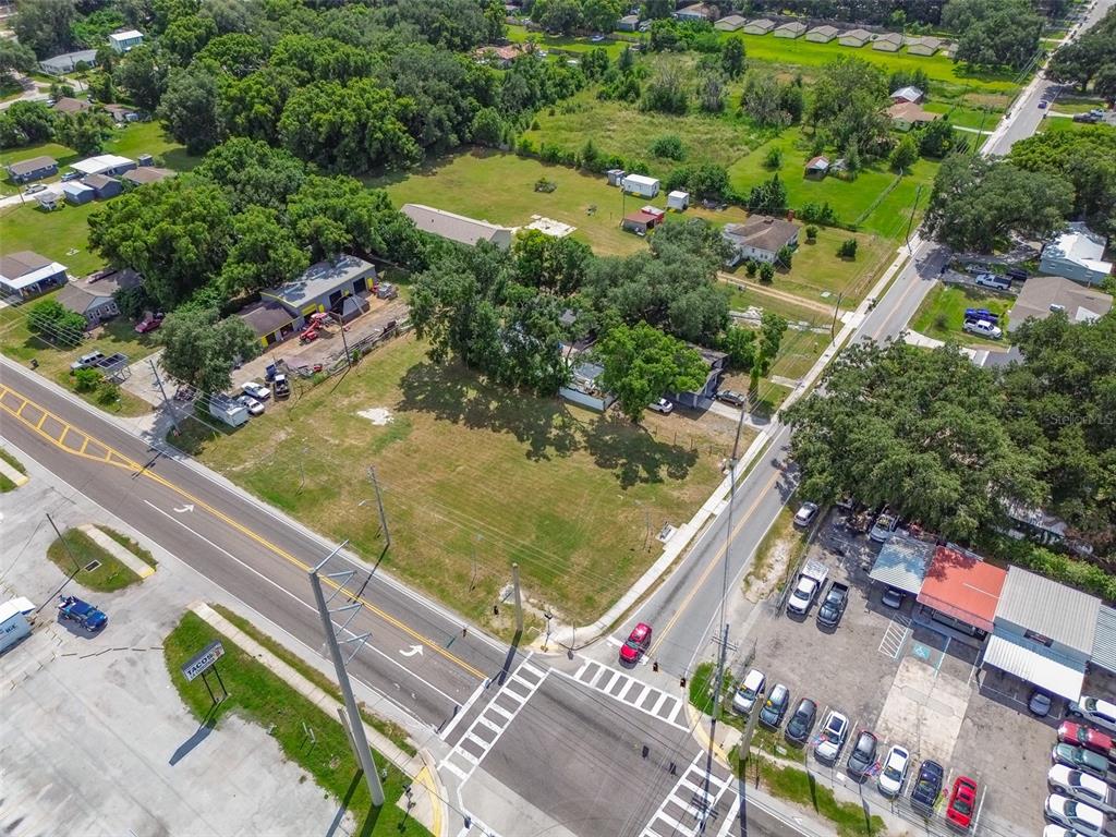 An aerial view shows a corner lot with a large grassy area and nearby buildings — 1336 N COMBEE ROAD, LAKELAND, FL