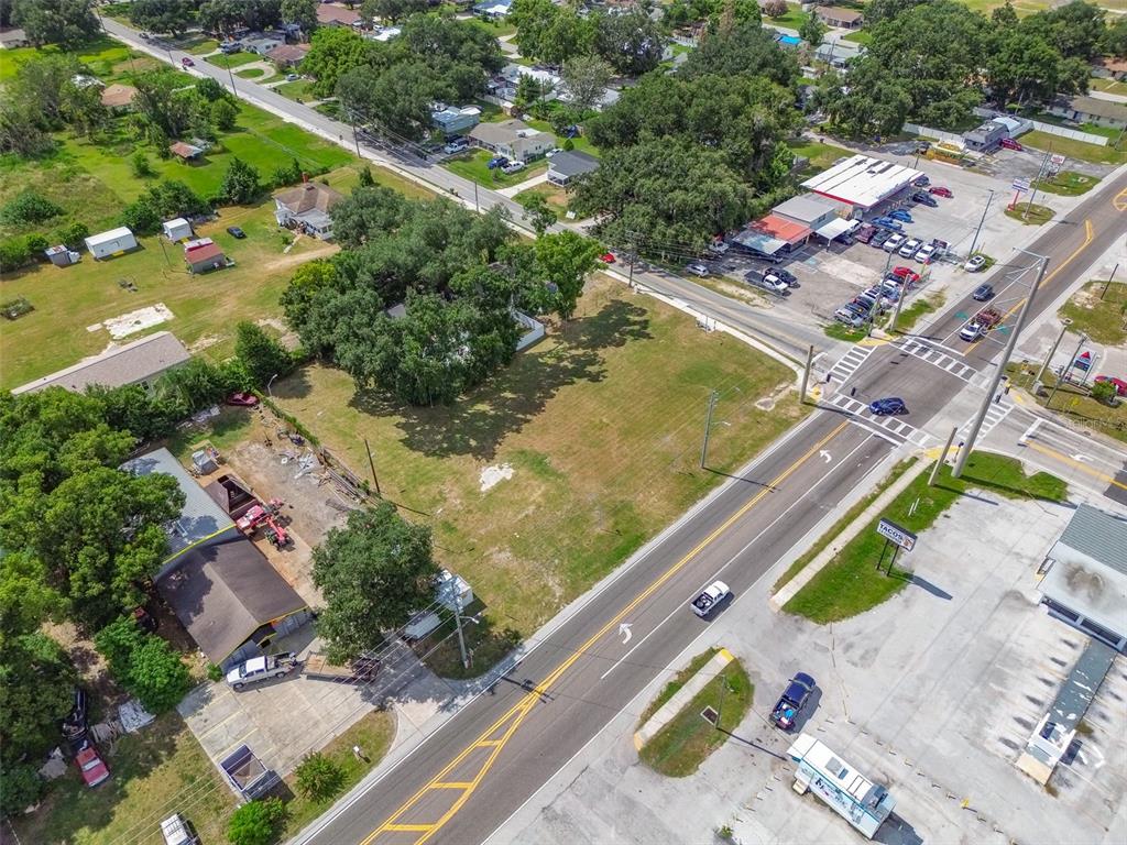 An aerial view shows a vacant grassy lot situated between a commercial building and road — 1336 N COMBEE ROAD, LAKELAND, FL
