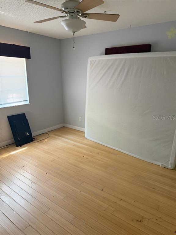 An empty bedroom with light wood flooring, a ceiling fan, and a mattress leaning against a wall — 101 WALKER DRIVE, INTERLACHEN, FL