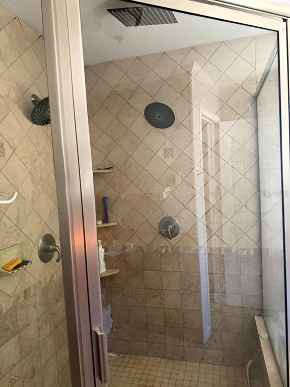 A tiled walk-in shower features a glass door, dual showerheads, and built-in corner shelving — 101 WALKER DRIVE, INTERLACHEN, FL