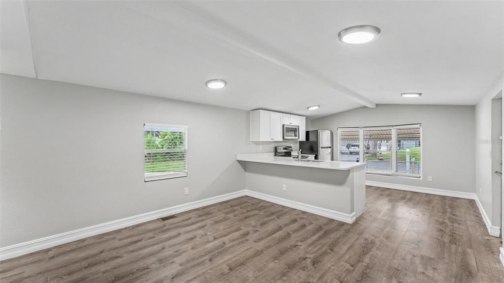 A kitchen features white cabinetry, stainless steel appliances, a quartz countertop, and wood-look flooring — 212 KAYLOR DRIVE, AUBURNDALE, FL